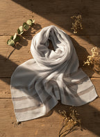 Striped scarf on a wooden surface with leaves and flowers