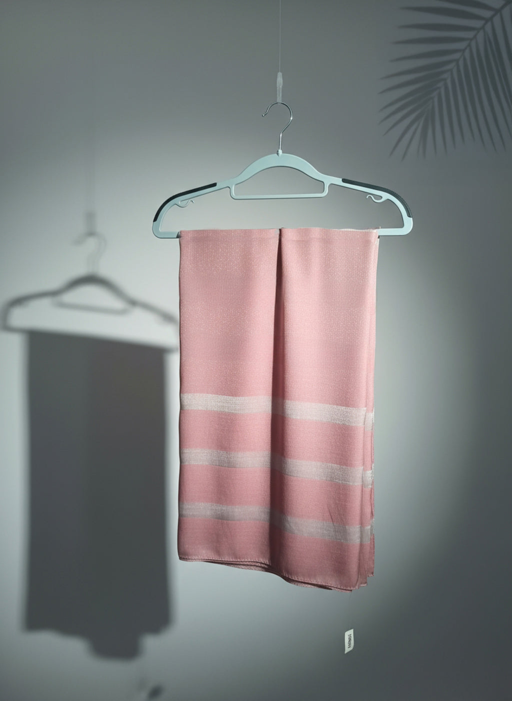 Pink striped towel hanging on a white hanger against a gray wall.