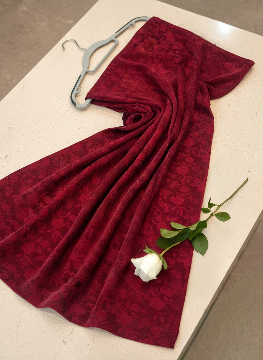 Red  on a white surface with a white rose and hanger.